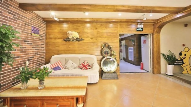 Een receptiezone met een houten wand, een receptiebalie, een bank met kussens en een potplant.