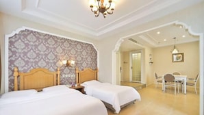 Een hotelkamer met twee bedden, een zithoek met een tafel en stoelen, en een kroonluchter.