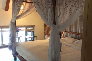 Un dormitorio con cama, ventana con vistas y una mesa con sillas.