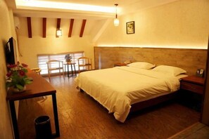A bedroom with a large bed, a bedside table, a chair, a small table with flowers, and a window. - Jinyatai Holiday Manor (Hengyang)