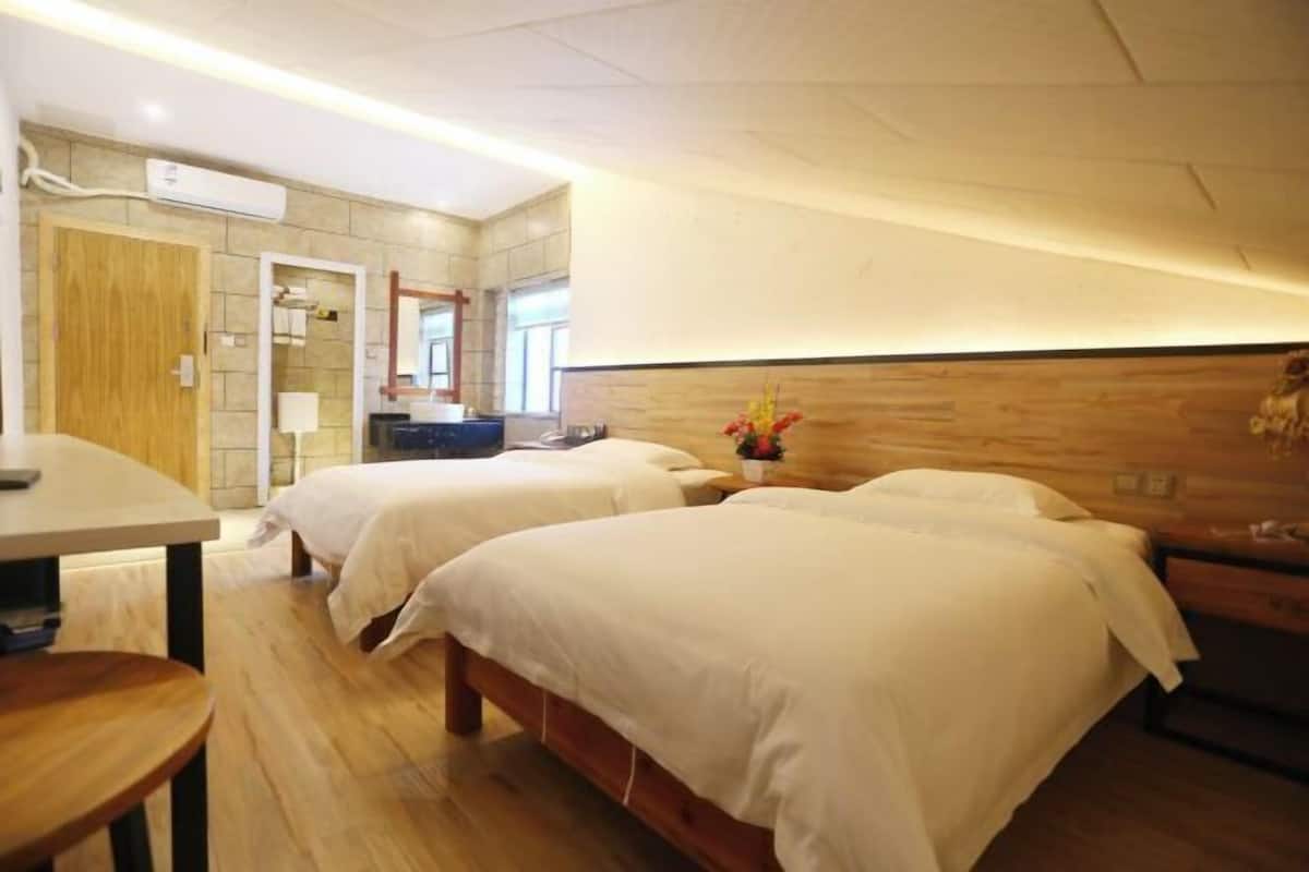 A hotel room with two beds, a wooden headboard, a small table, and a mirror.