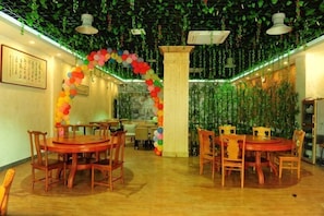 A restaurant with round tables and chairs, a decorative archway, and hanging plants. - Jinyatai Holiday Manor (Hengyang)