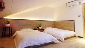 A hotel room with two beds, a wooden headboard, a small table with a vase, and an air conditioning unit. - Jinyatai Holiday Manor (Hengyang)
