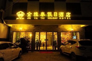 The exterior of Jin Ya Tai Holiday Hotel with a brick facade and illuminated signage.