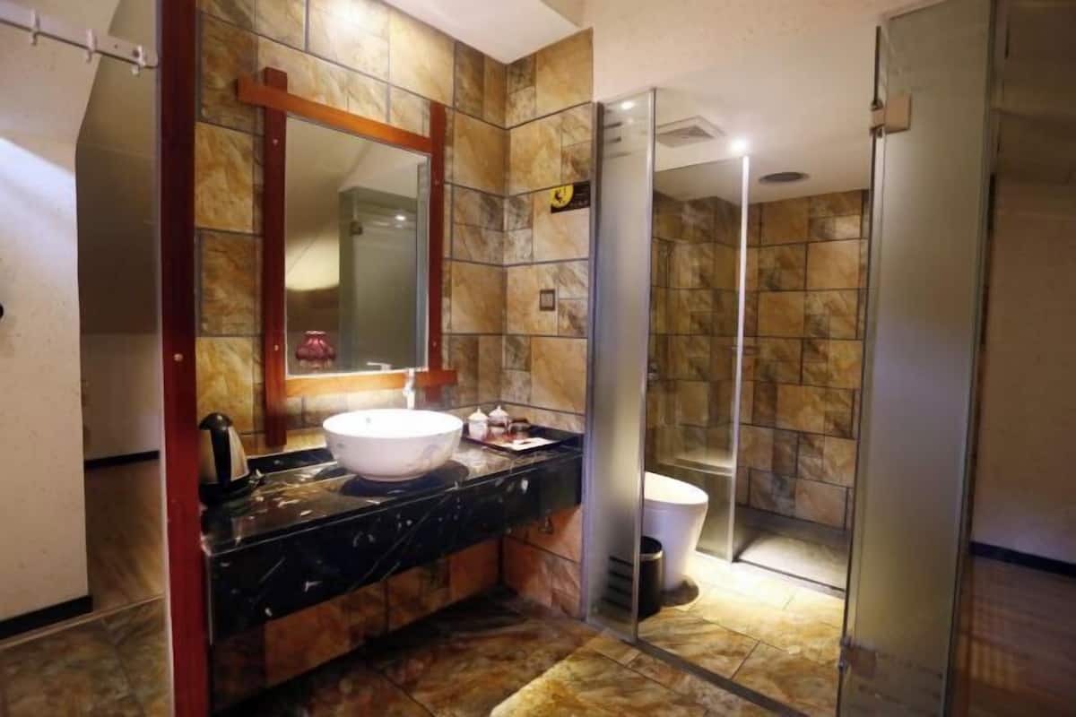 A bathroom with a marble wall, a large mirror, a white sink, and a toilet.