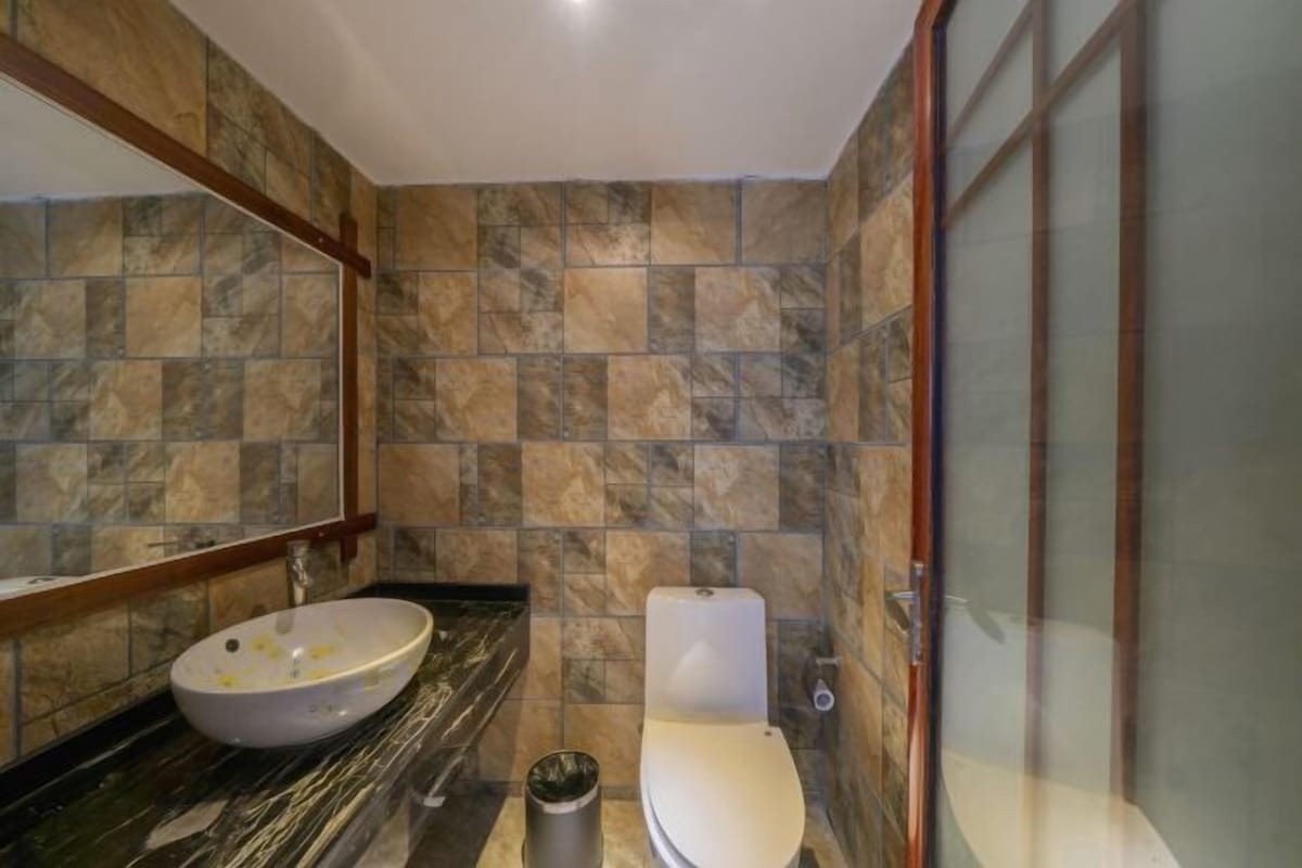 A bathroom with a marble sink, a toilet, and a glass shower enclosure.