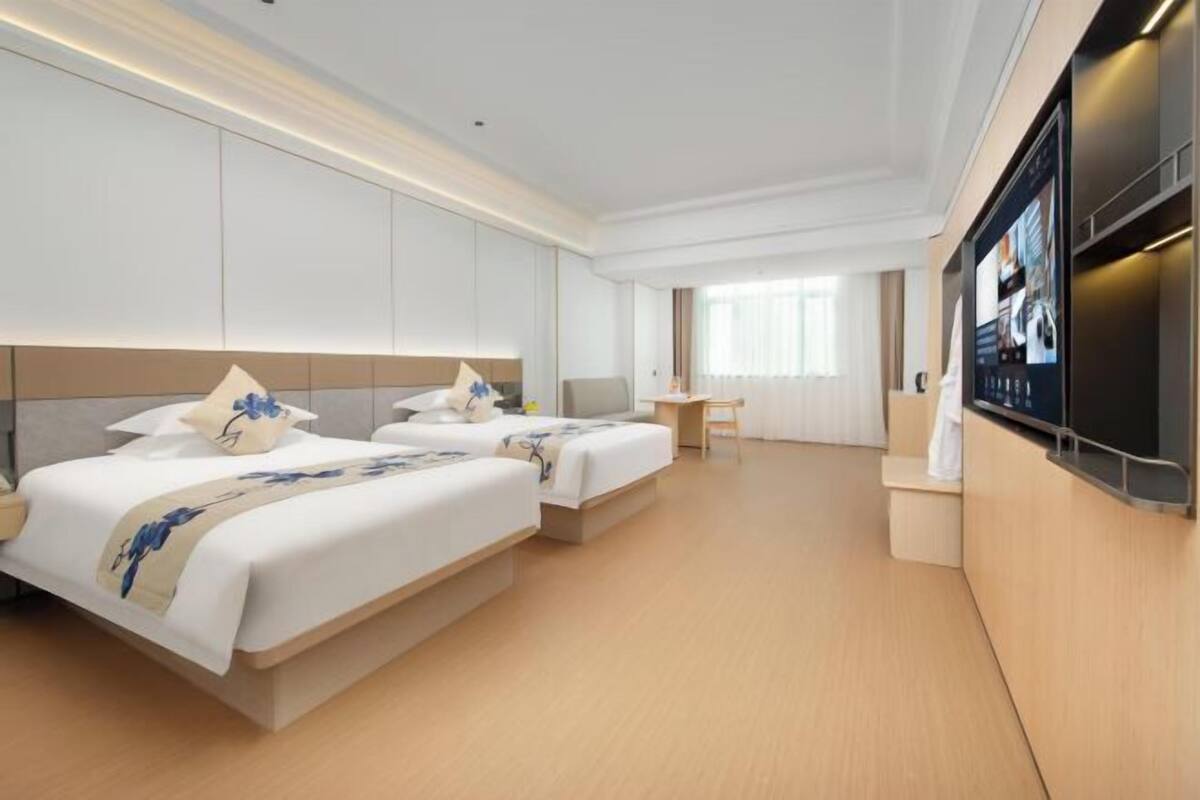Une chambre d’hôtel avec deux lits, un bureau et une télévision.