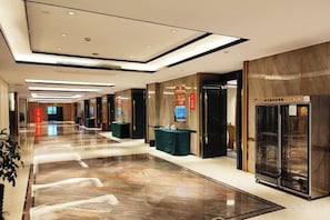 Un pasillo de hotel con piso pulido, un mostrador de recepción y un refrigerador minibar.