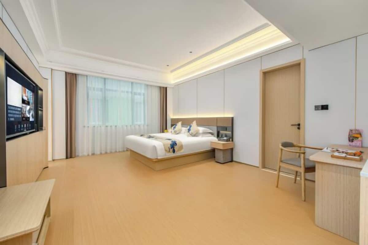 Une chambre d’hôtel équipée d’un lit, d’une table de chevet, d’une chaise et d’un téléviseur fixé au mur.
