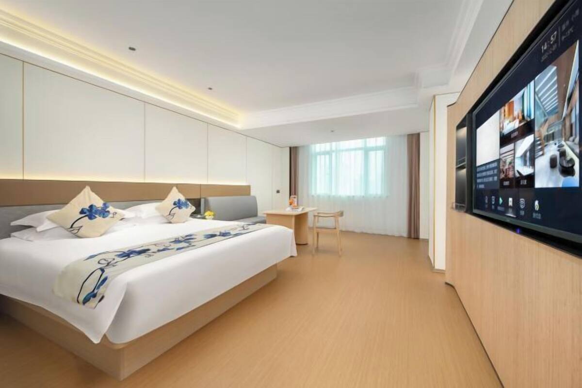 Une chambre d’hôtel moderne équipée d’un grand lit, d’un bureau et d’un téléviseur diffusant des images.