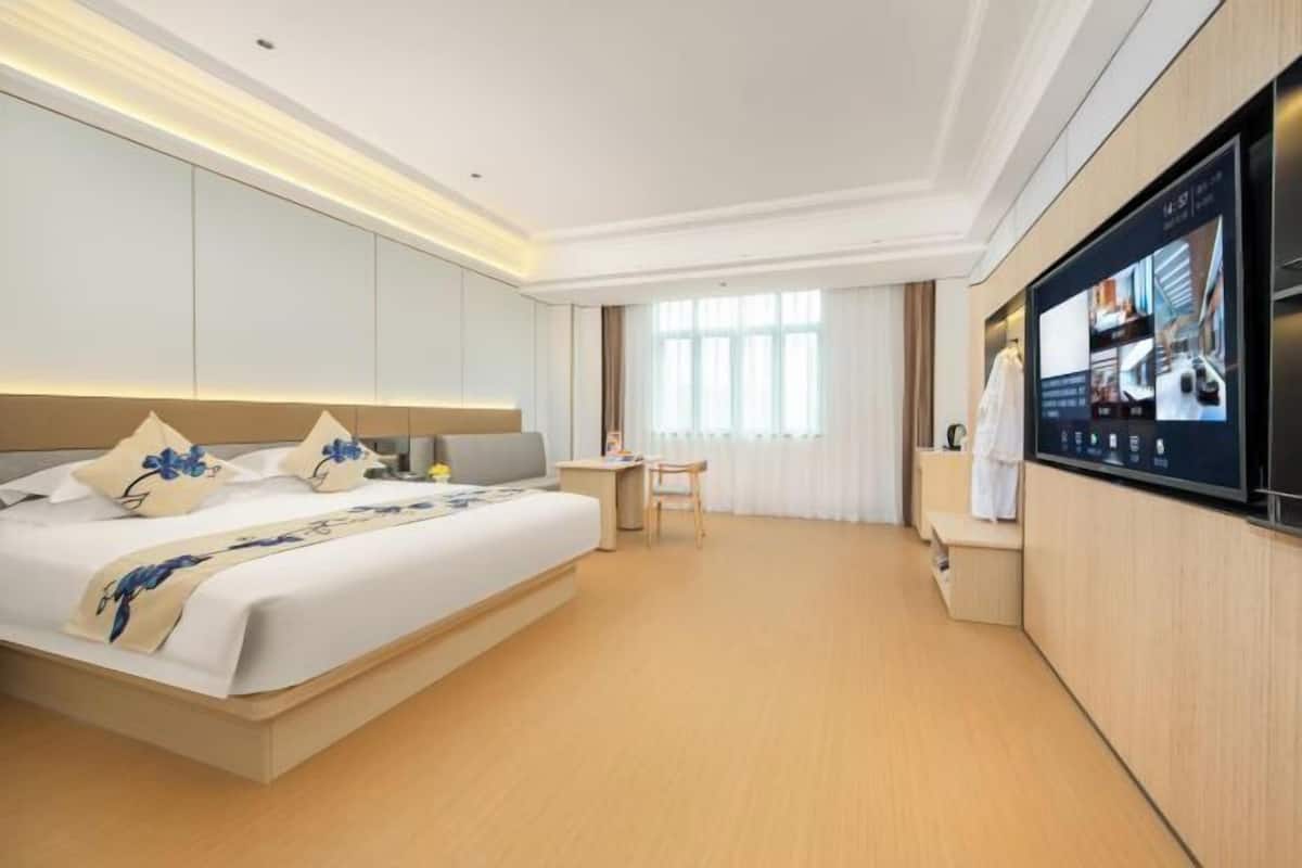 Une chambre d’hôtel avec un grand lit, un bureau, une télévision et une armoire.