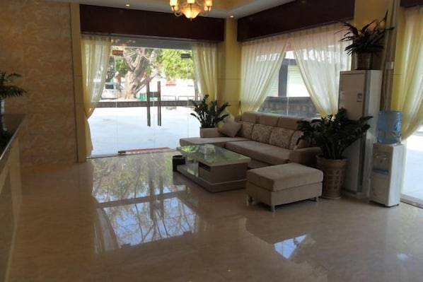A hotel lobby with a sofa set, a coffee table, a refrigerator, and a large window with curtains. - Jixing Express Hotel (Shenzhen)