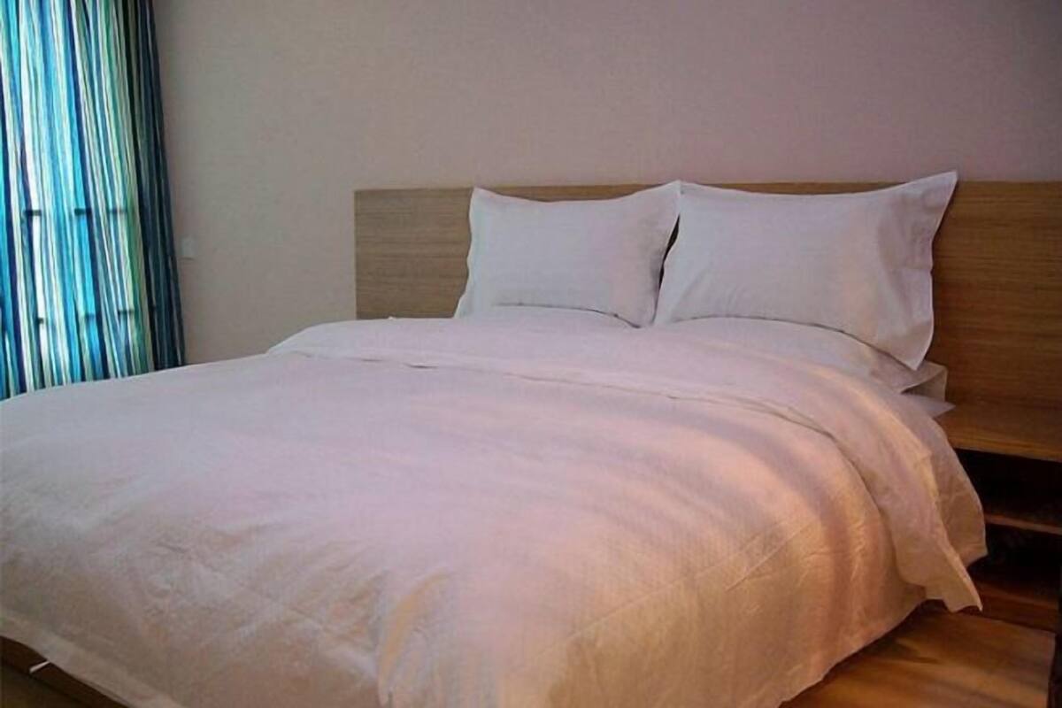 A neatly made bed with a wooden headboard and white bedding.