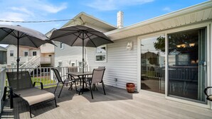 Une terrasse couverte avec une table et des chaises, des parasols et un petit tapis.