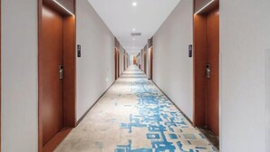 A long, narrow hotel corridor with wooden doors on both sides and a patterned carpet. - Four Seasons Jun'an Hotel (Fuzhou Jinshan Subway Station Branch) (Fuzhou)
