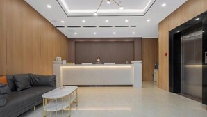 A modern reception area with a reception desk, a sofa, and a coffee table. - Four Seasons Jun'an Hotel (Fuzhou Jinshan Subway Station Branch) (Fuzhou)