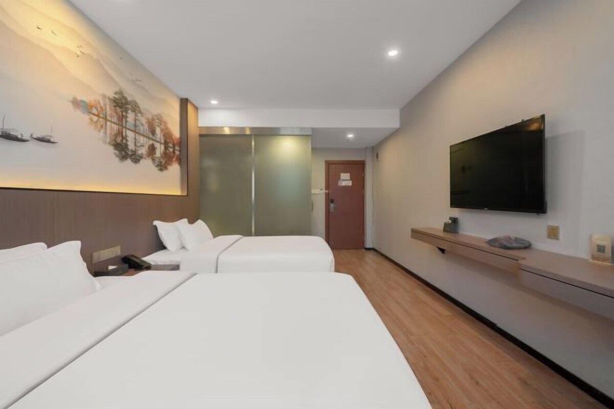A hotel room with two beds, a flat-screen TV, a wooden floor, and a wall-mounted artwork.