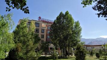 A multi-story hotel with a red sign, surrounded by trees and a clear sky.