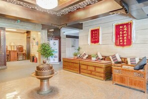Un vestíbulo con una mesa de recepción, un jarro decorativo y adornos tradicionales de la cultura china.