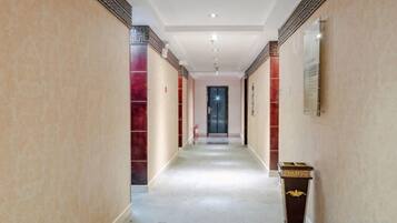 A hallway with a carpeted floor, a door at the end, and a small table with a decorative item on the right.