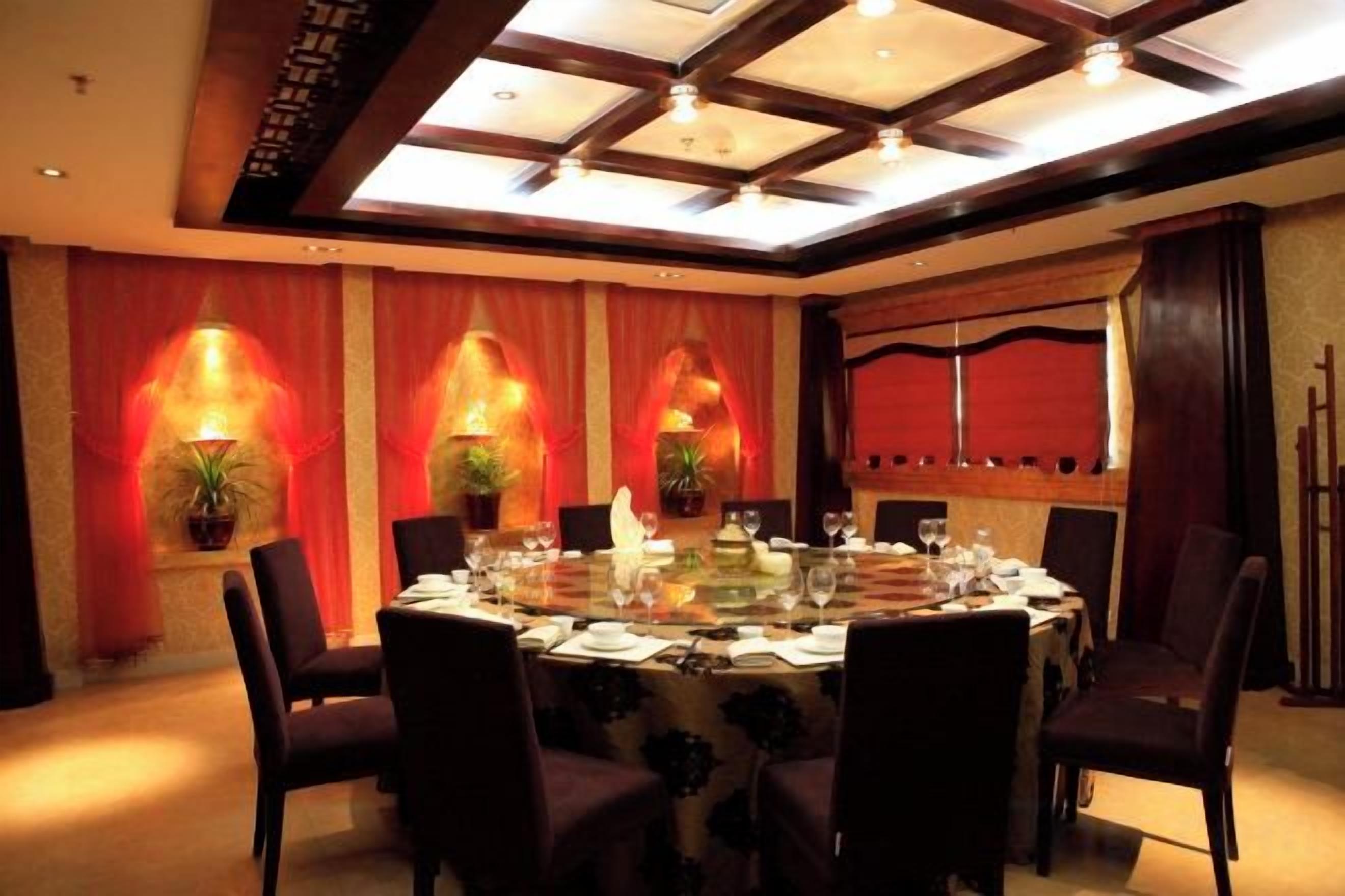 A conference room with a round table, chairs, and red curtains.