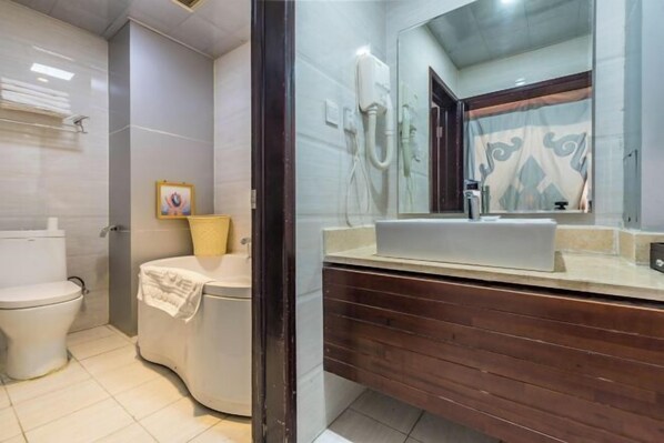 A bathroom with a toilet, a bathtub, a sink, and a mirror. - Padma Chumig Garden Hotel (Lhasa)