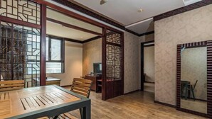 A room with a wooden dining table, chairs, a TV, and a decorative screen. - Padma Chumig Garden Hotel (Lhasa)