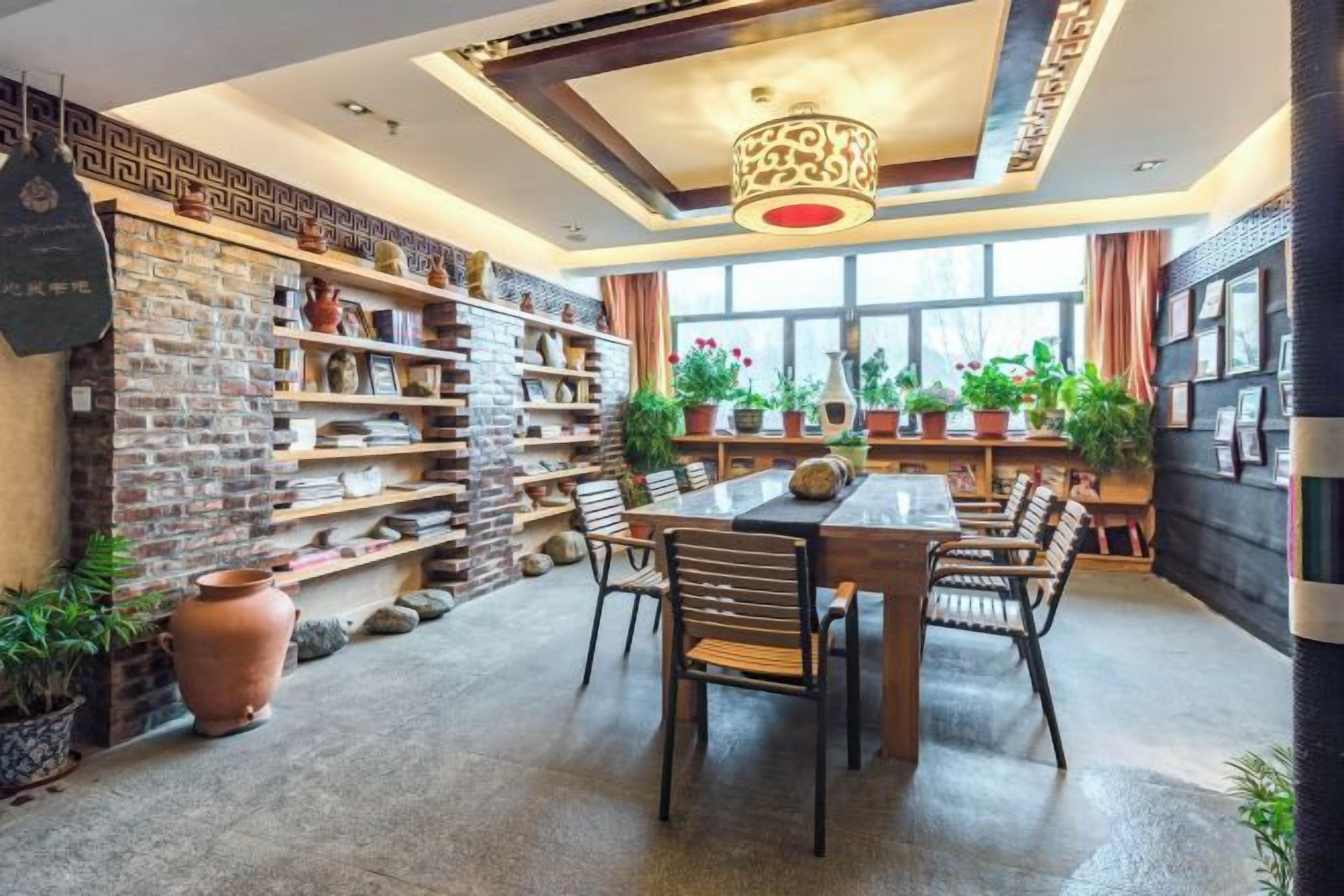 A dining area with a brick wall, shelves with decorative items, and a table with chairs.