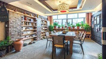 A dining area with a brick wall, shelves with decorative items, and a table with chairs.