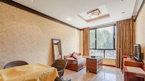 A room with a dining table, a sofa, a TV, and a large window. - Padma Chumig Garden Hotel (Lhasa)