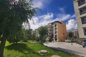 Zona residencial con edificios de varios pisos, un espacio con césped y cielo despejado.