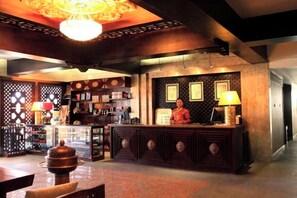 A reception area with a wooden reception desk, a chandelier, and a wall with framed pictures. - Padma Chumig Garden Hotel (Lhasa)