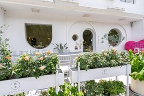 Un bâtiment blanc avec de nombreuses fenêtres, un balcon orné de plantes et un décor en forme de cœur rose.