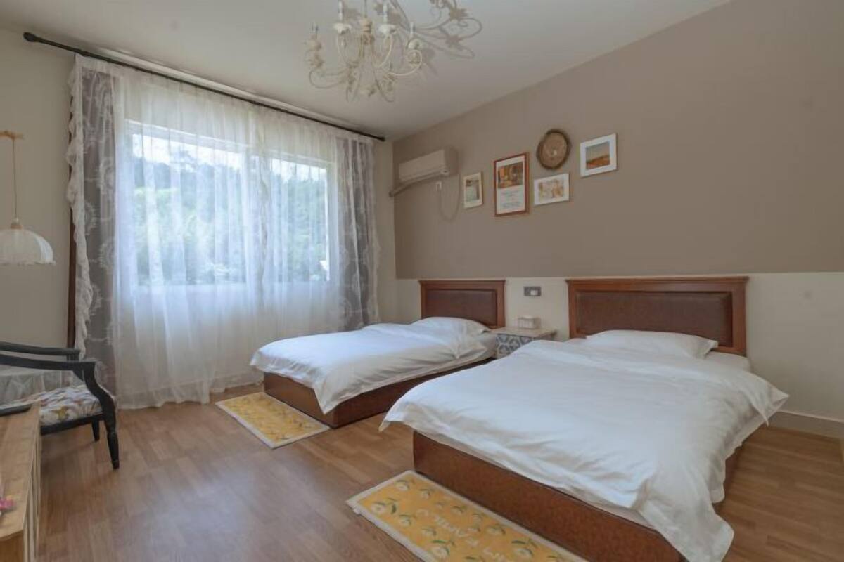 Quarto com duas camas, um candelabro, uma escrivaninha e uma cadeira.
