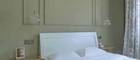 A bedroom with a bed, bedside tables, a mirror, and a chandelier.