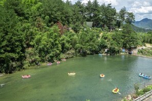 A river with several inflatable boats and a forested area in the background. - Huanxi Homestay (Hangzhou)