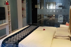 A hotel room with a bed, a TV, a wardrobe, and a bathroom visible through a glass partition. - Kaisheng Hotel Luochuan (Luochuan)