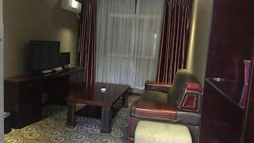 Une chambre d’hôtel équipée d’un bureau, d’une télévision, d’un canapé et d’une moquette à motifs.