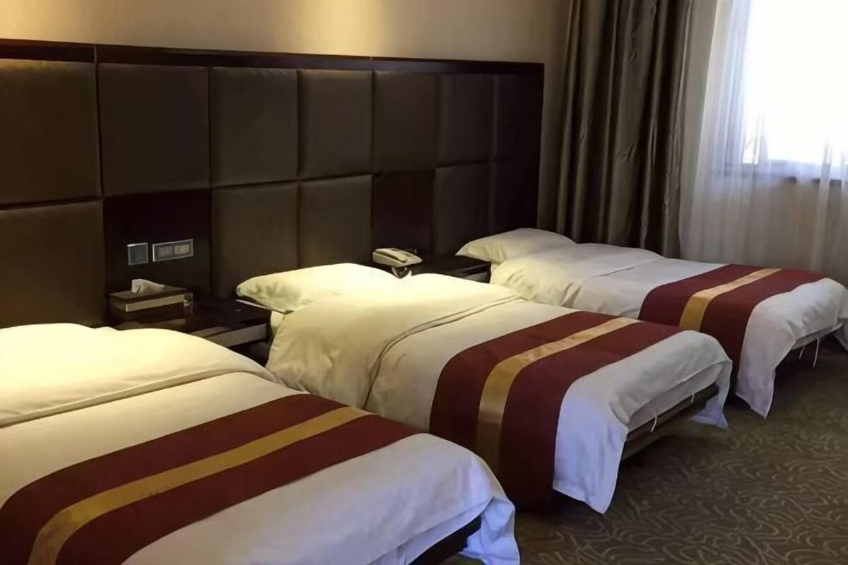 Ein Hotelzimmer mit zwei Betten, einem Kopfteil, einem Nachttisch und einem Telefon.