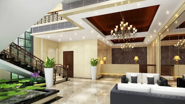 Eine moderne Lobby mit Marmorboden, einer Treppe, einem Empfangstresen und einem Kronleuchter.