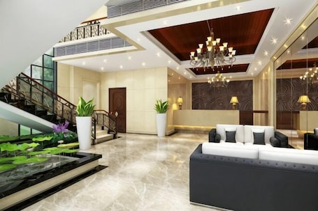 A modern lobby with a marble floor, a staircase, a reception desk, and a chandelier.. Kaisheng Hotel Luochuan