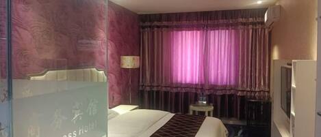 A hotel room with a bed, a television, a desk, and a window with curtains.