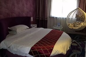 A bed with a red and white bedspread, a hanging chair, and a bedside table with a lamp. - Kaisheng Hotel Luochuan (Luochuan)
