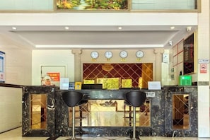 A hotel reception area with a marble counter, two bar stools, a clock, and a sign indicating a no-smoking policy. - Anyi Fenghe Hotel (Anyi)