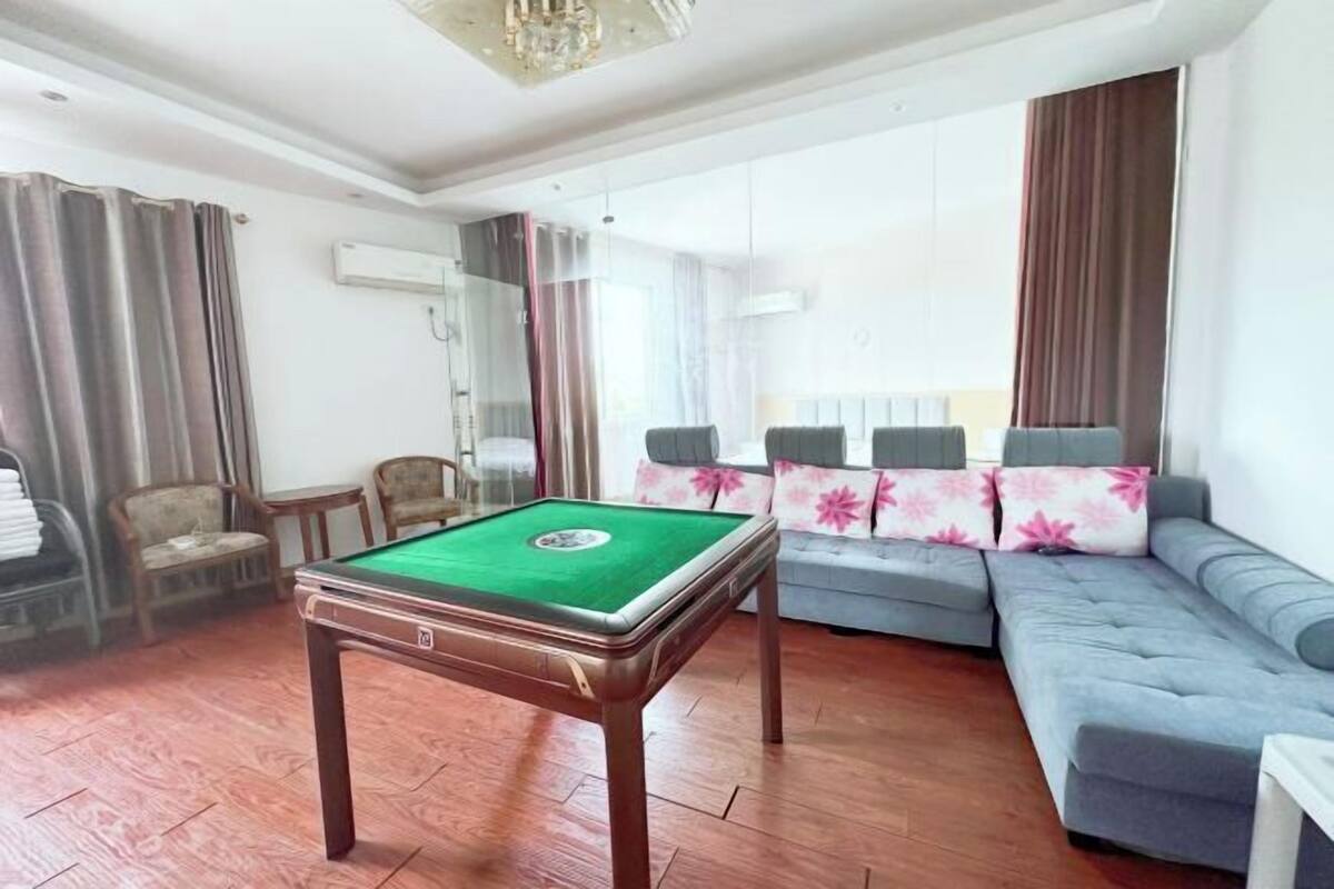 A living room with a pool table, a sofa, and a large window with curtains.