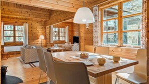 Ein gemütliches Blockhaus-Interieur mit Essbereich, Holzwänden und großen Fenstern.