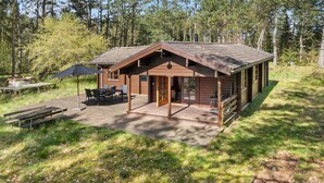 Eine rustikale Holzhütte mit überdachter Veranda, Essbereich und kleiner Terrasse.
