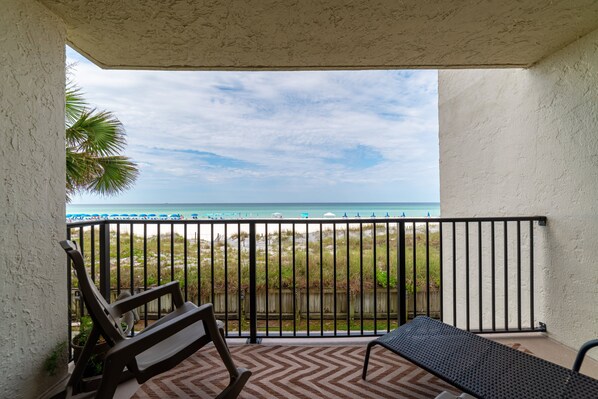 A balcony with a view of the beach and ocean.