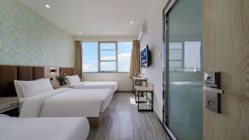 Habitación de hotel con dos camas, televisión, ventana con vistas y puerta corredera.