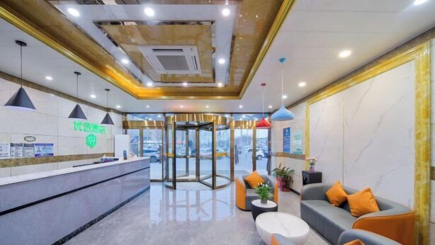 A modern reception area with a revolving door, seating arrangements, and a reception desk. - 99inn Selected (Beijing Huilongguan East Street Metro Station) (Beijing)